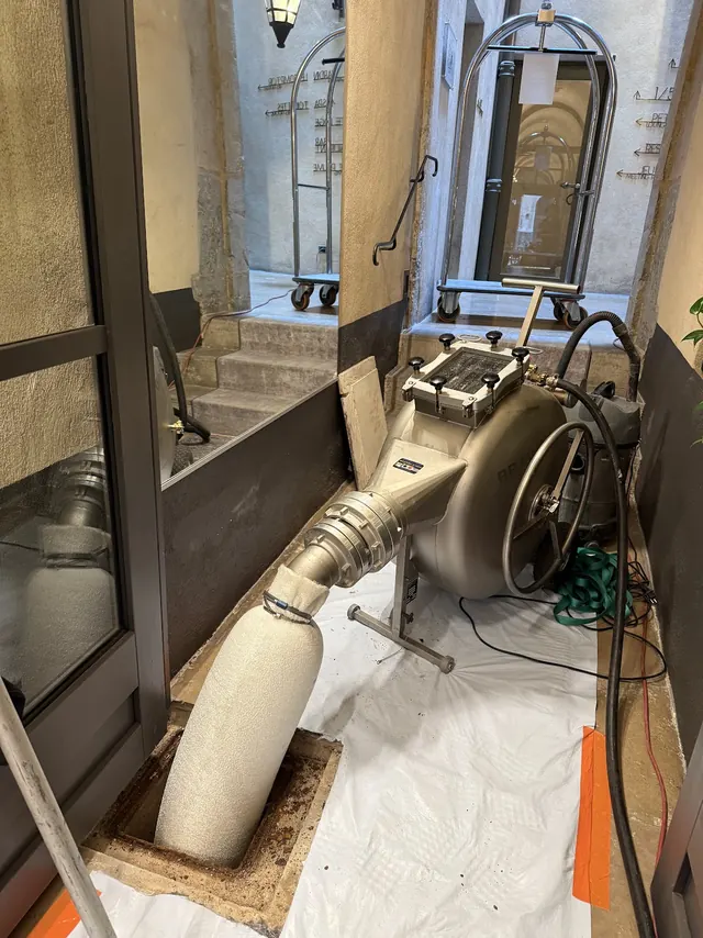 Machine de chemisage installée dans l'entrée d'un immeuble, la gaine engagée dans un regard